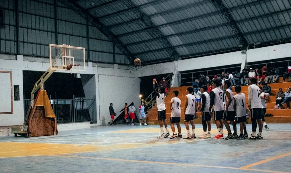 A group of men standing around a basketball court