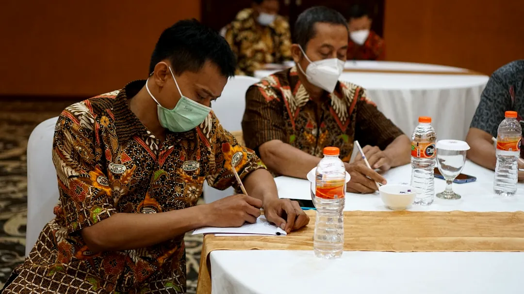 a group of people sitting at a table with masks on