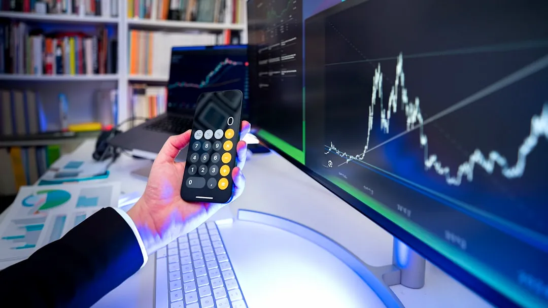 A man holding a remote control in front of a computer
