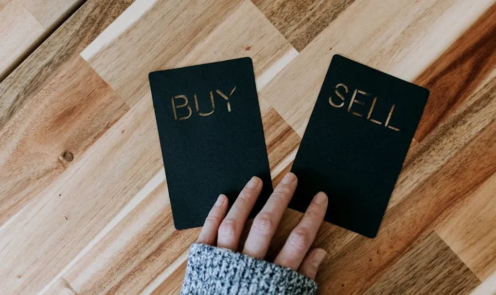 a person holding two small black books with the words buy and sell on them