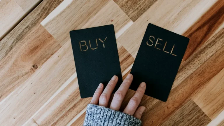 a person holding two small black books with the words buy and sell on them