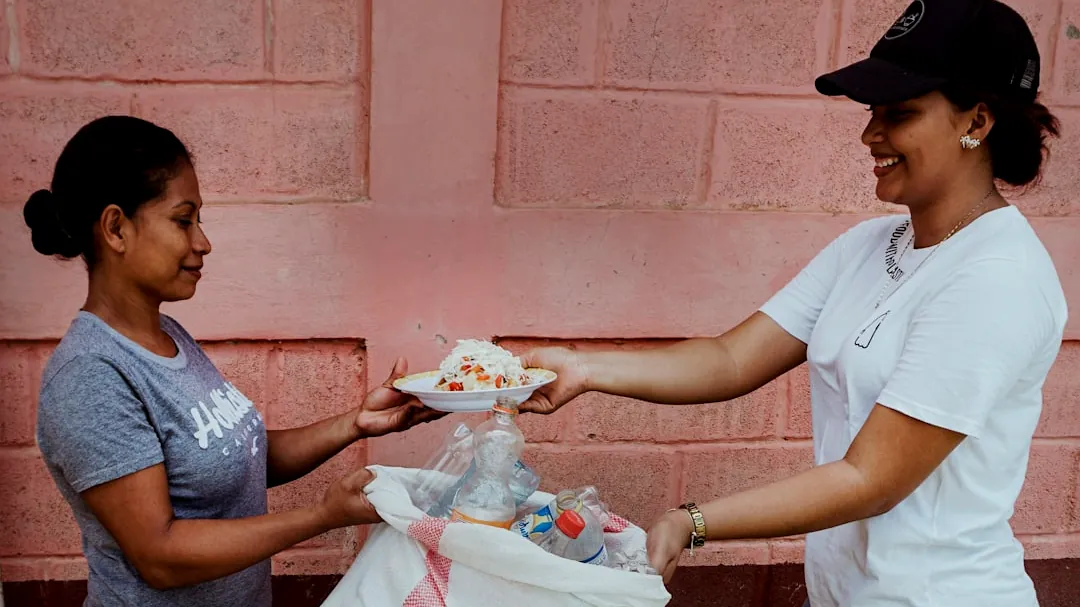 a woman handing another woman a plate of food