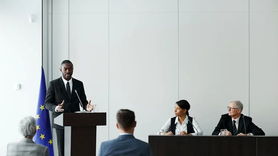 Business meeting featuring diverse professionals discussing important topics with a speaker at the podium indoors.