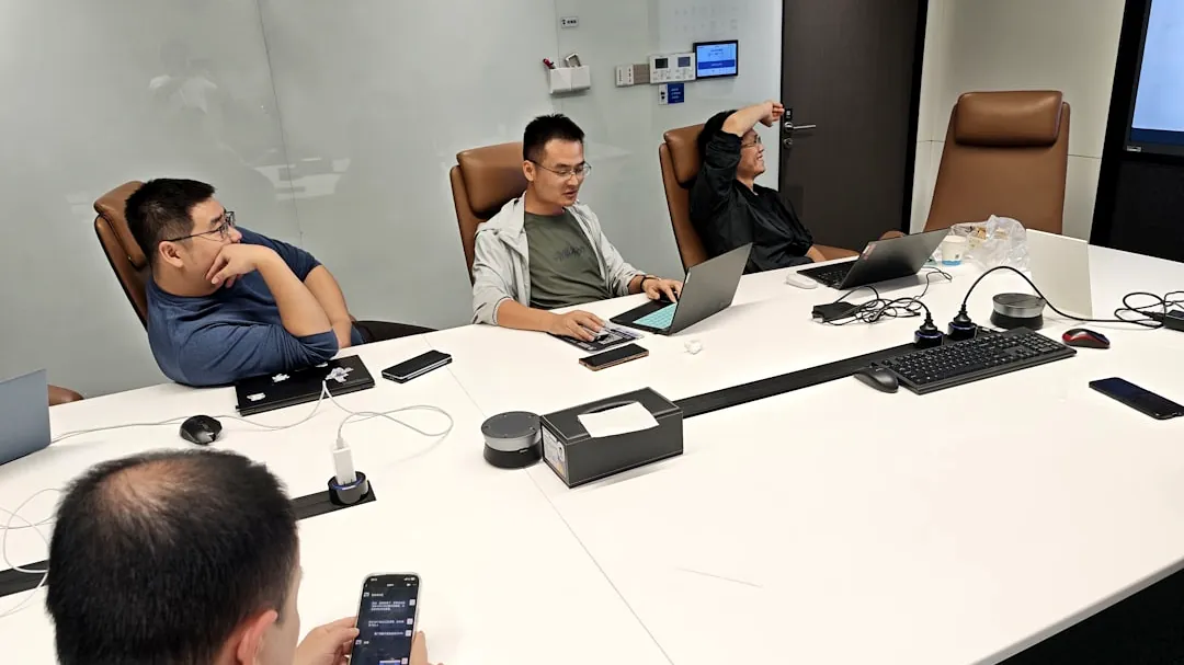 Four men in a meeting room with laptops.