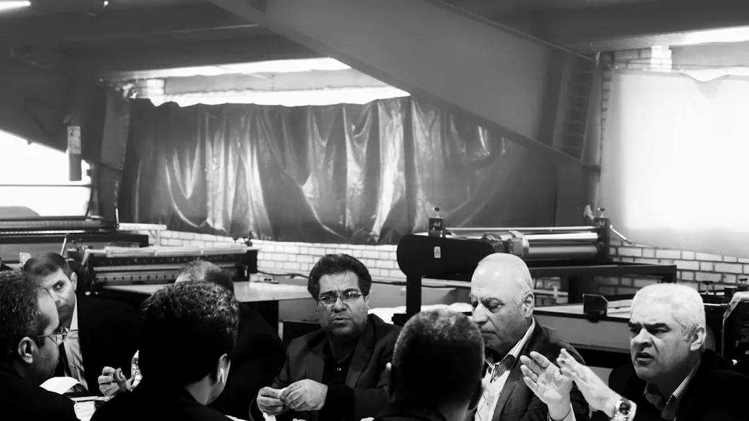 grayscale photography of group of person sitting indoors
