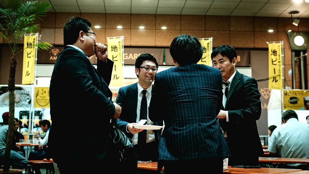 group of people standing in front of brown wooden table