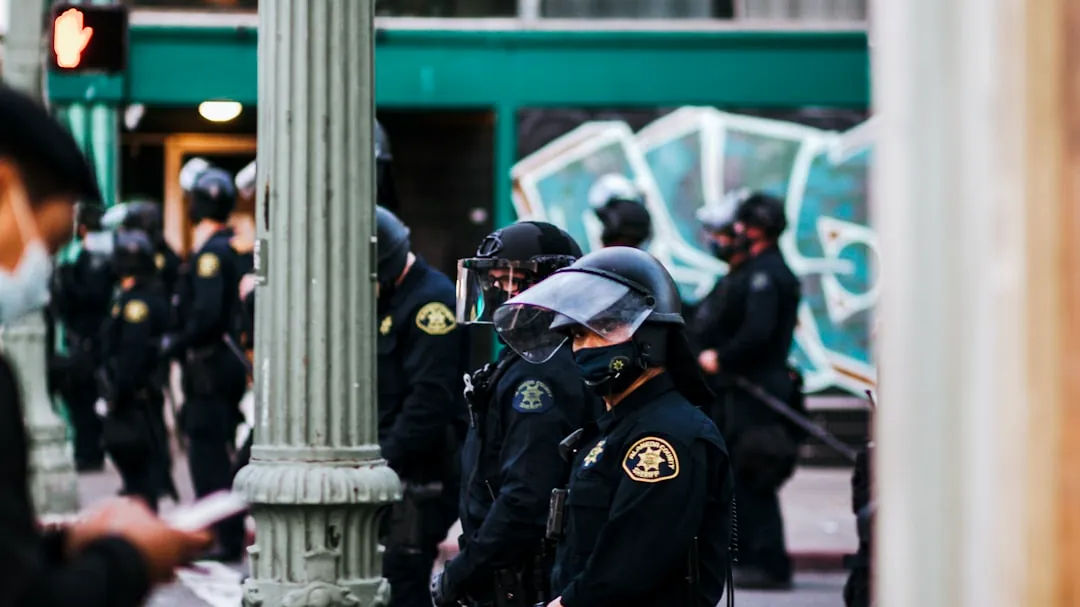 man in black police uniform standing near white concrete post during daytime