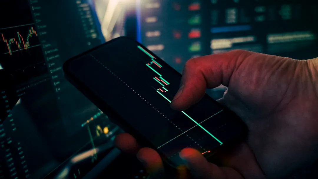 Trader analyzing stock market data on smartphone and phone