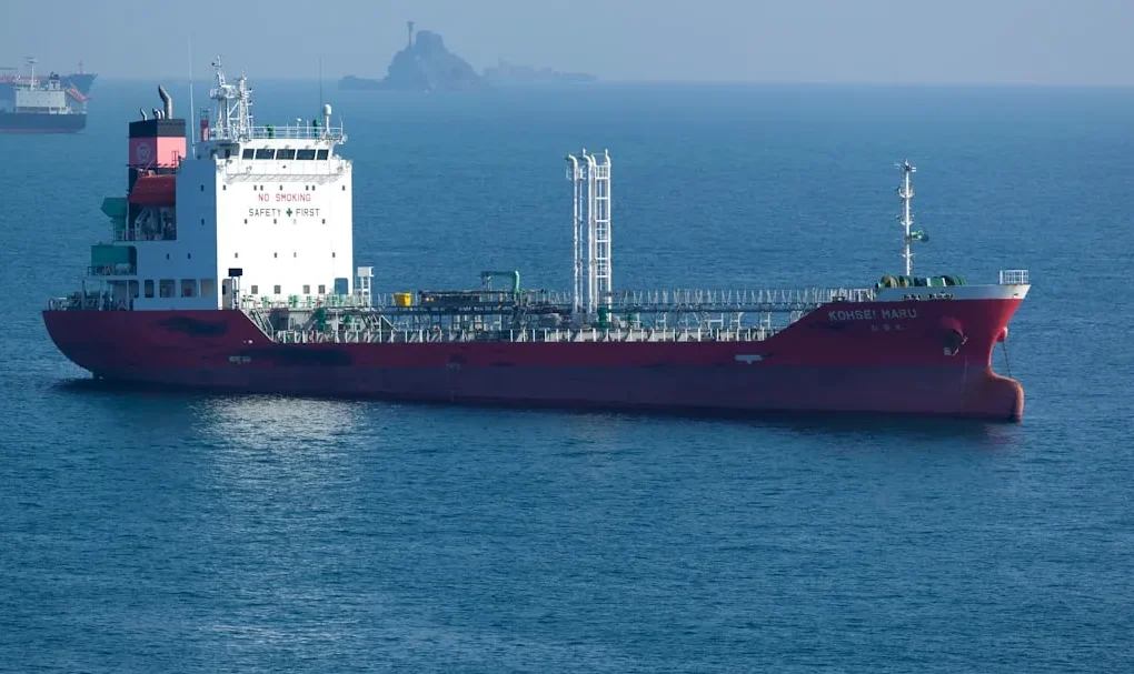 A large red tanker ship sails on the ocean.