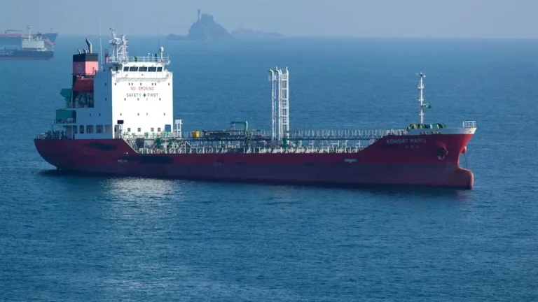 A large red tanker ship sails on the ocean.