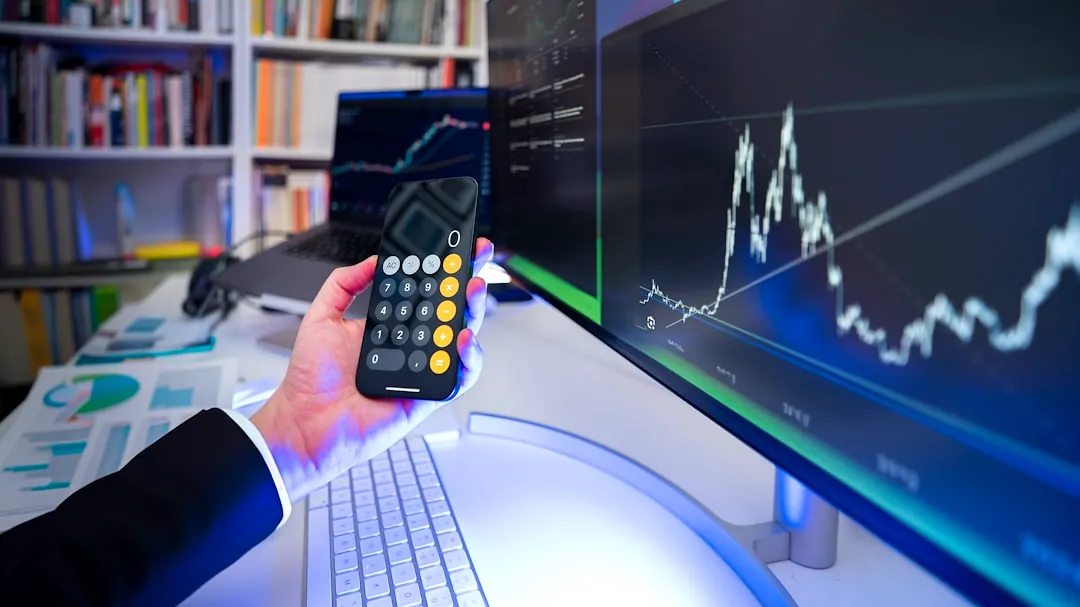 A man holding a remote control in front of a computer