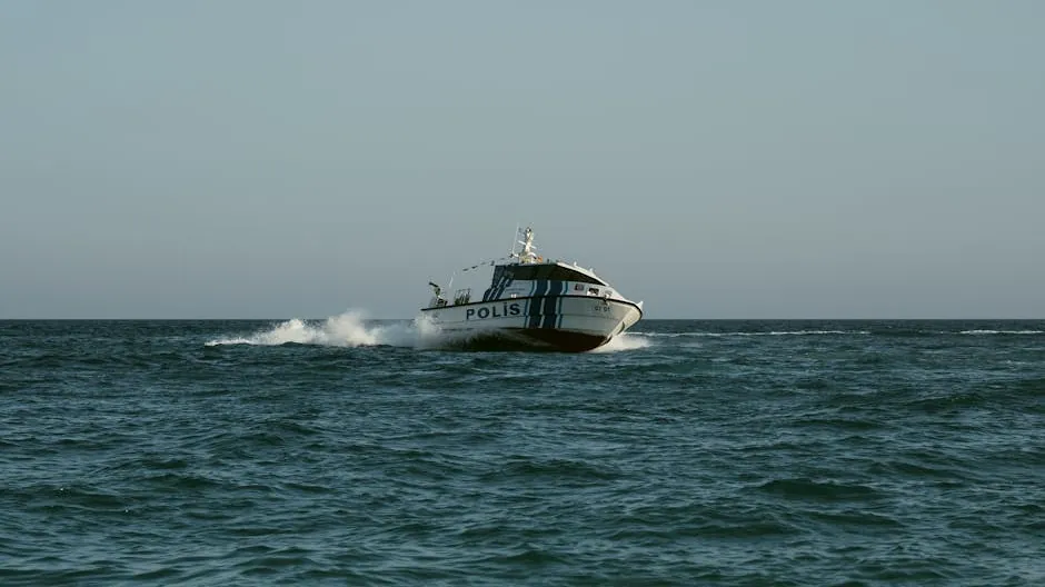 A police boat speeds across the open sea under clear skies, maintaining maritime security.