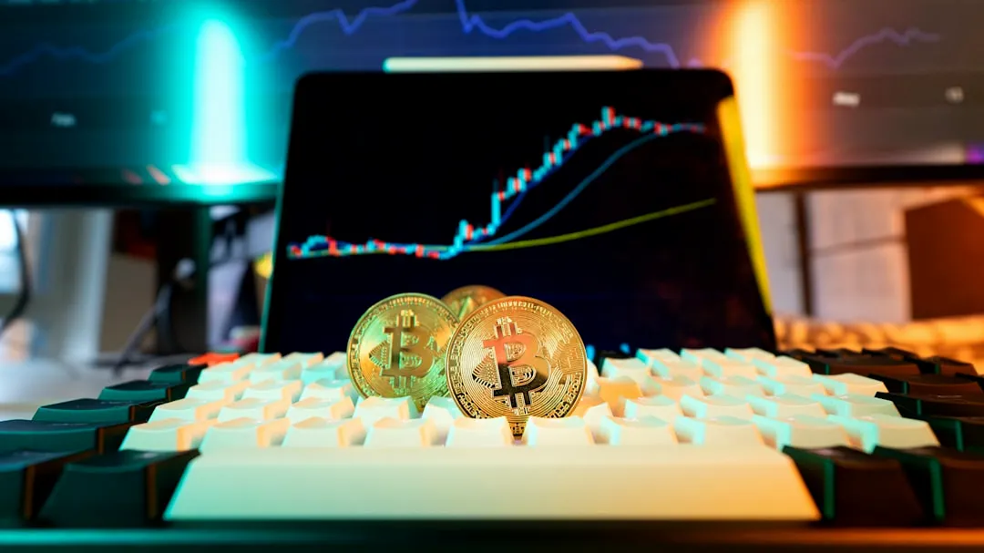 Bitcoin coins rest on a keyboard with stock charts.