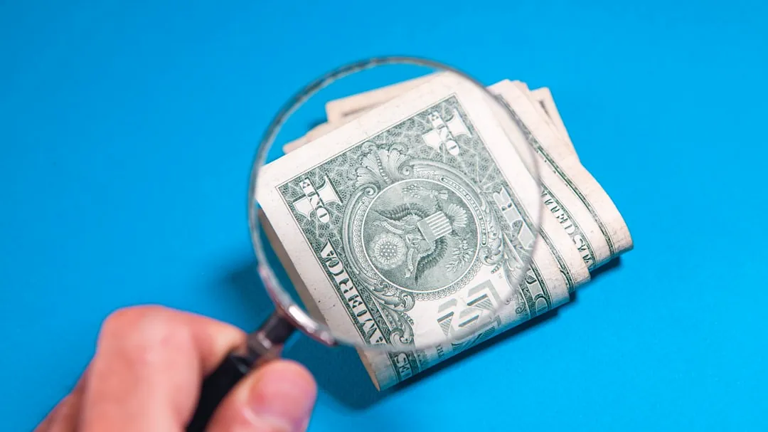 Magnifying glass over folded us dollar bills