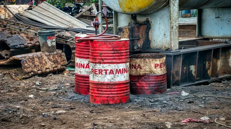 Old red metal barrels with inscription placed on ground in landfill in daylight