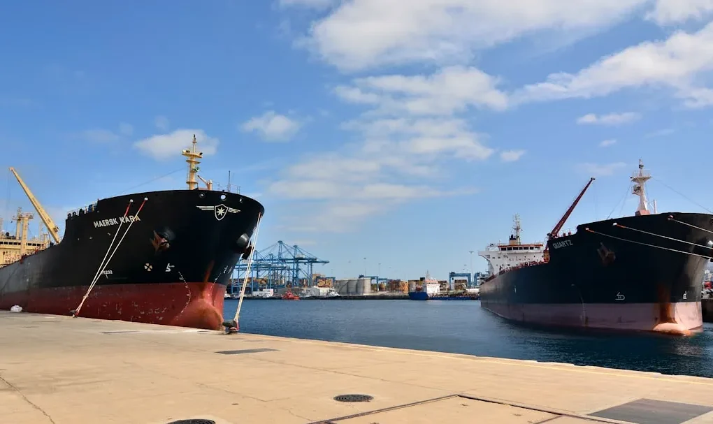 Two cargo ships docked at a harbor.
