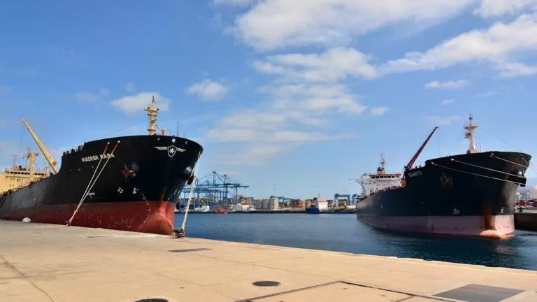 Two cargo ships docked at a harbor.