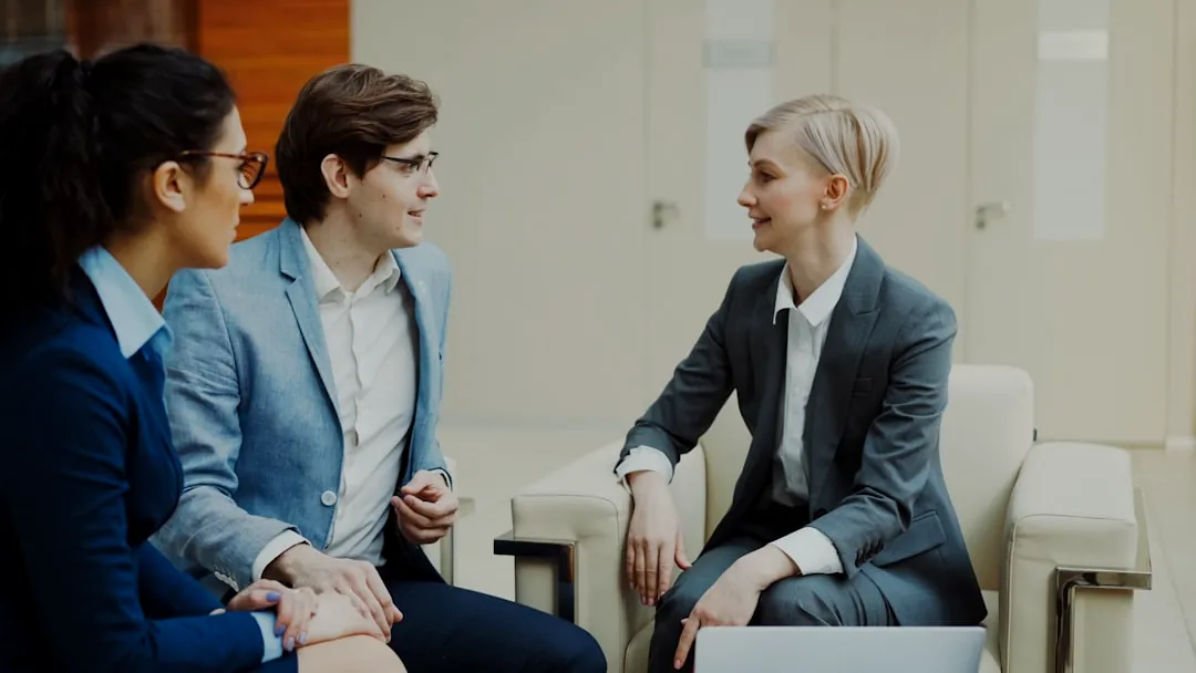 Three professionals in business attire conversing indoors.