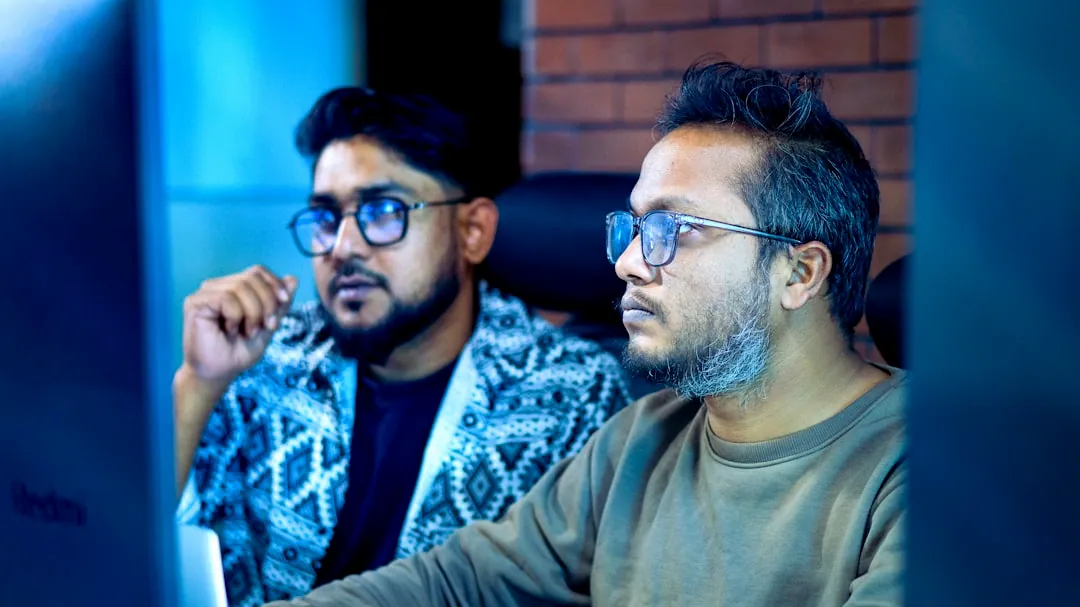 Two men looking intently at a computer screen.
